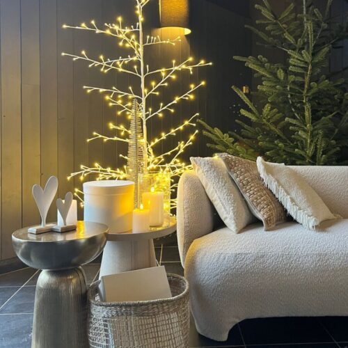 Canapé blanc à l'entrée du restaurant éphémère Cocon d'Hiver avec un sapin lumineux